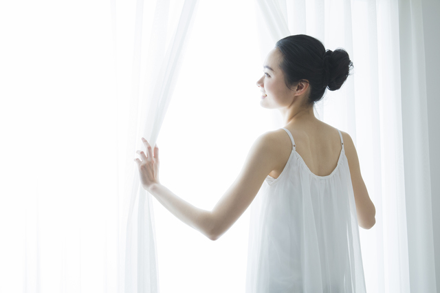 カーテンを開ける女性