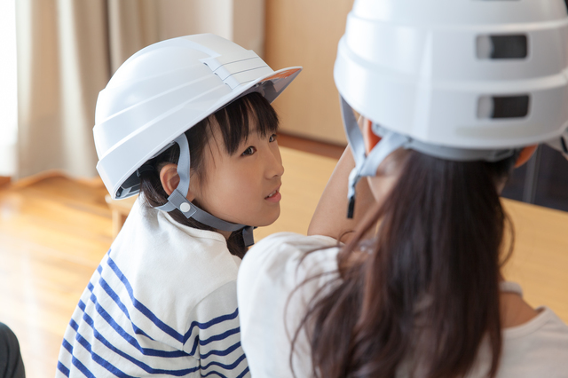 防災用のヘルメットを被った子ども