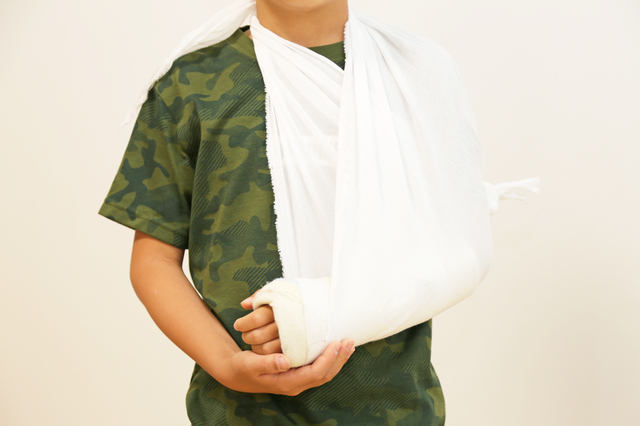 三角巾で腕を吊るす人