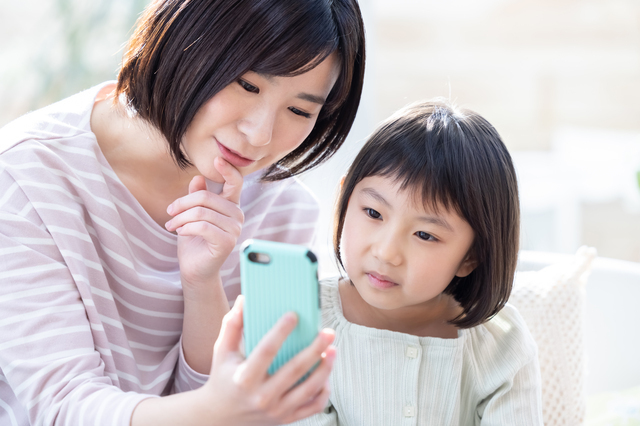 大人と子どもが一緒にスマホの画面を見ている様子