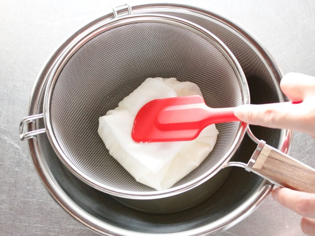 キッチンペーパーで中身を包み、ゴムベラで押して水気を切る様子