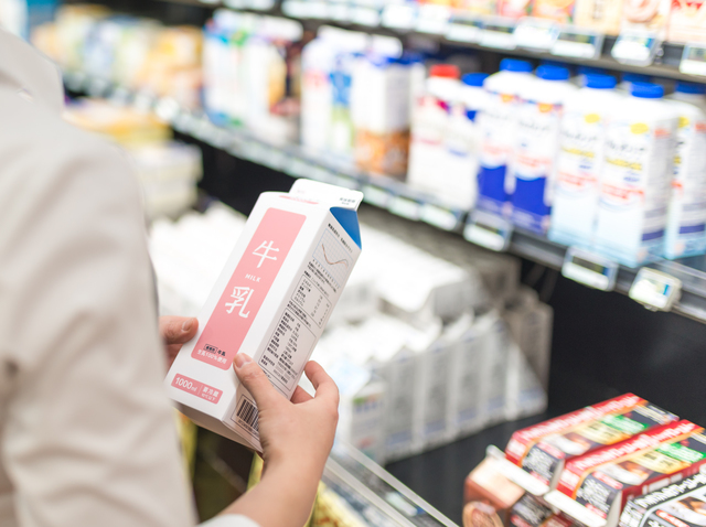 スーパーで売られている牛乳を手に取る様子