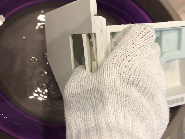 洗剤投入ケースを水洗いする様子