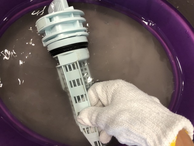 軍手で排水フィルターをこすり洗いする様子