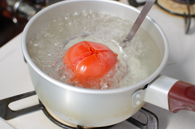 沸騰した鍋にトマトを入れる様子