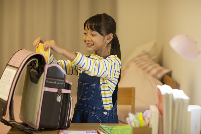 ランドセルに荷物を入れる子ども