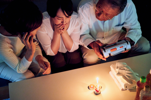 ろうそくの火を囲む家族