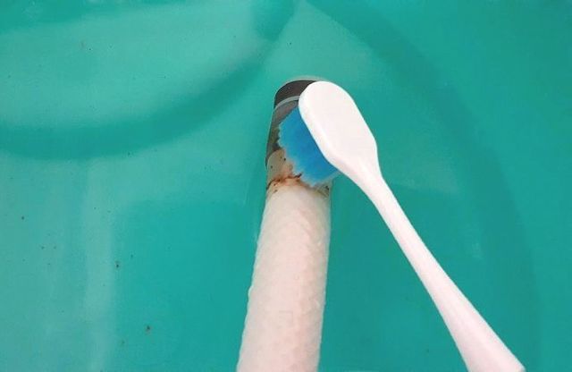 止水栓内部の汚れを古い歯ブラシでこする様子
