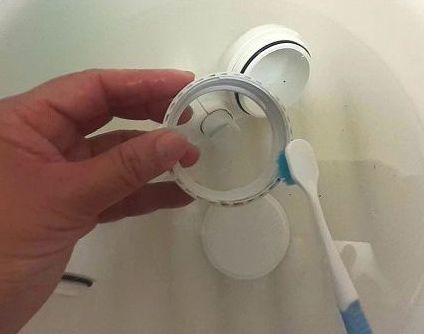 シャワーヘッドのパーツを古い歯ブラシでこする様子