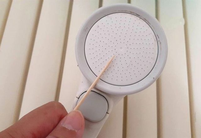 シャワーヘッドの目詰まりをつまようじで処理する様子