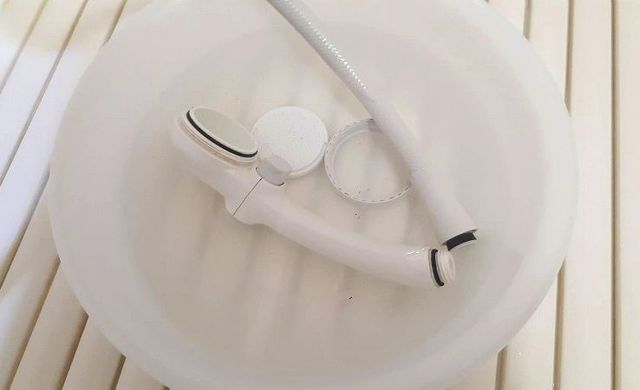 分解したシャワーヘッドをつけおき液につけている様子