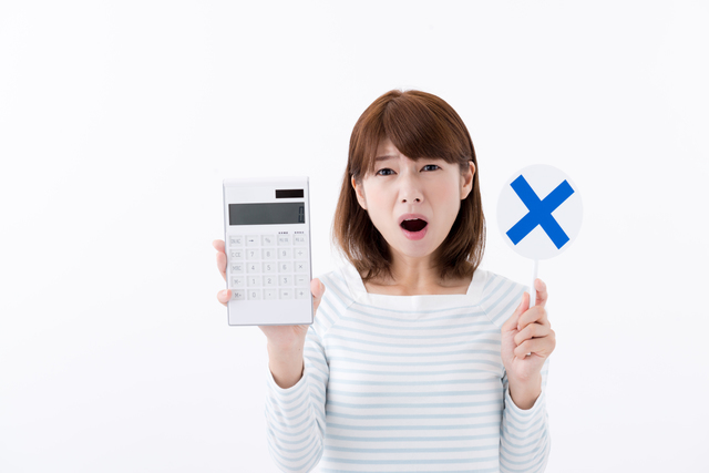 電卓をバツマークを持つ女性