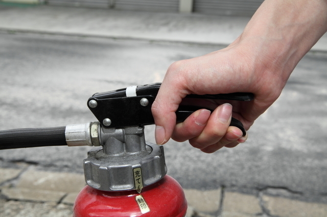 消火器のレバーを握る