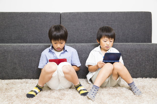 携帯ゲームをする子どもたち