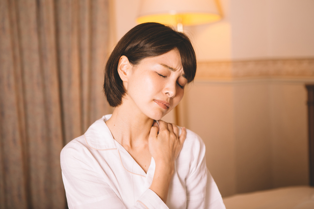 肩をおさえる女性